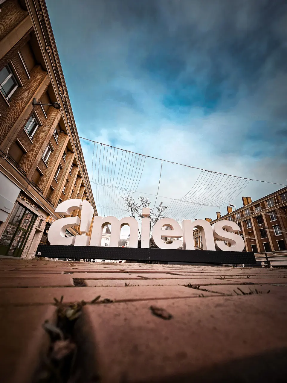 Les lettres géantes d'Amiens au pied des immeubles, sous un ciel bleu