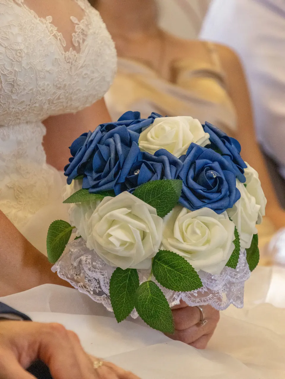 Le bouquet de roses bleues et blanches entre les mains de la mariée