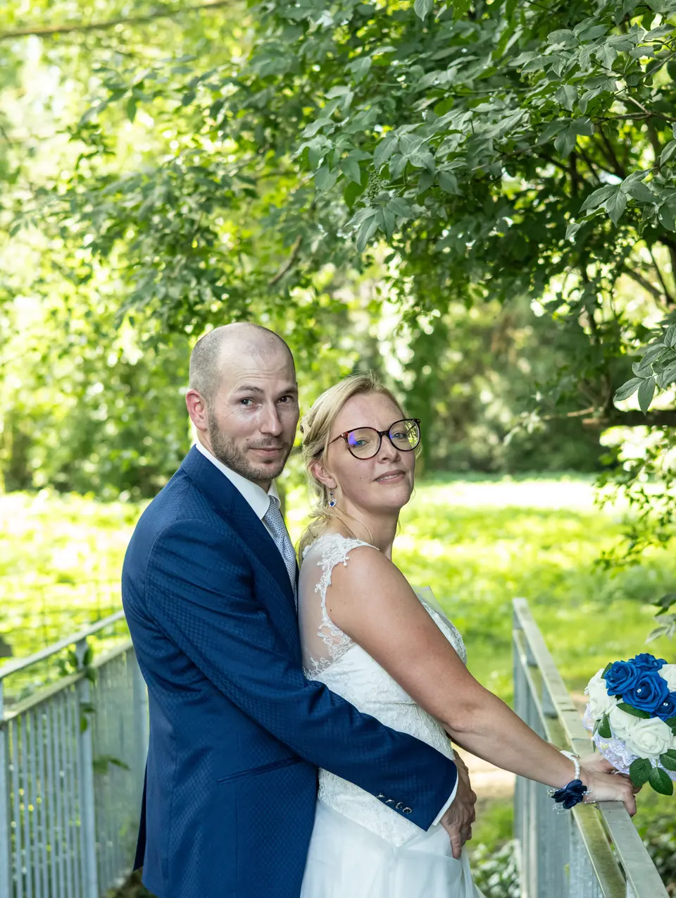 Les mariés enlacés dans un parc, sourire aux lèvres